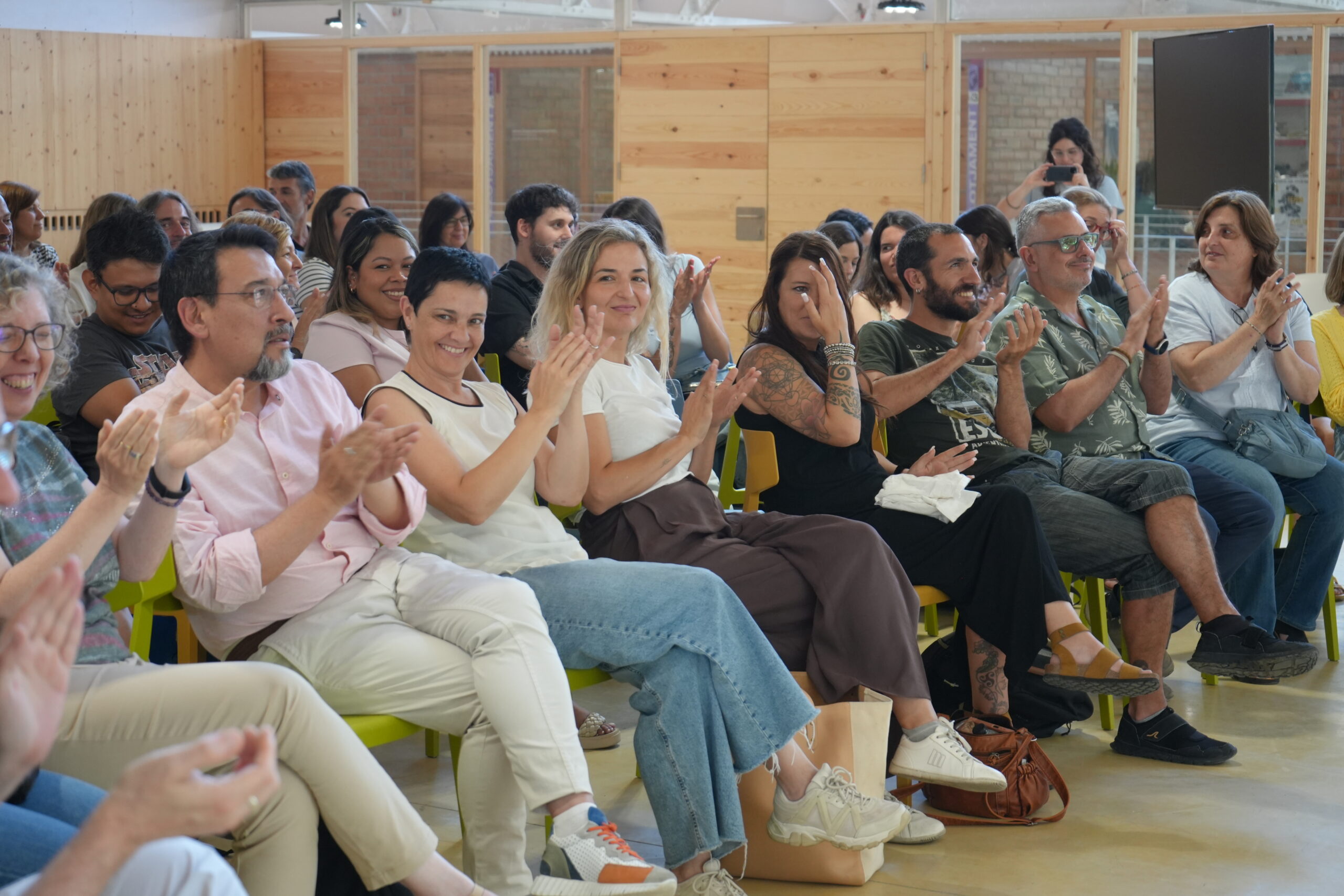 Personas de EDUVIC aplaudiendo con entusiasmo en una asamblea.