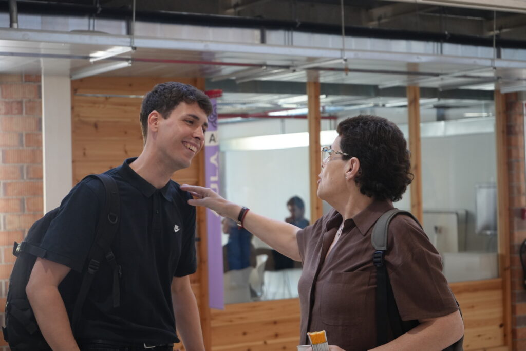 DSC01347 Profesional de EDUVIC saludando con afecto a un compañero joven en un espacio de trabajo compartido.